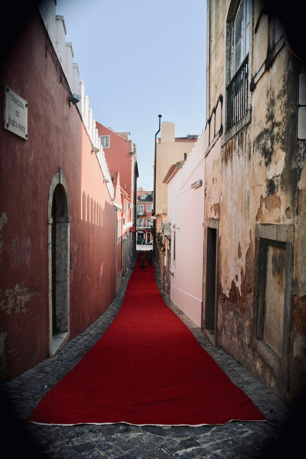 red hallway between brown concrete buildings during daytime