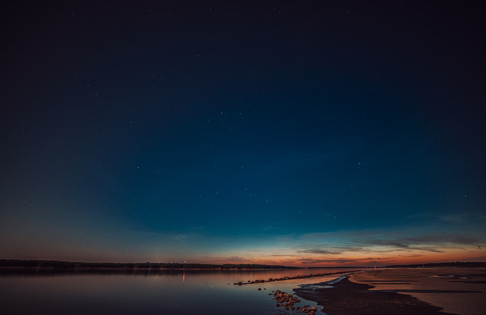 specchio d'acqua sotto il cielo blu durante la notte