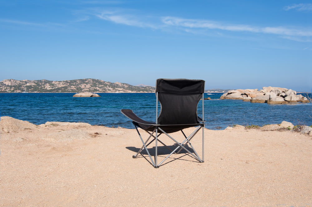 chaise pliante noire et grise sur la plage pendant la journée