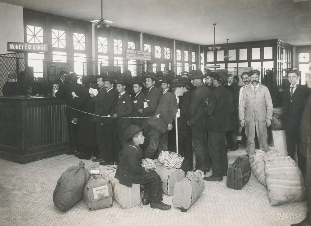 Foto en escala de grises de un grupo de inmigrantes con bolsas dentro