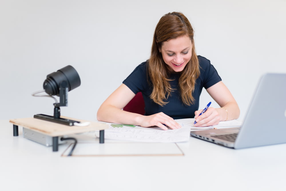 a woman sitting at a desk writing on a notebook