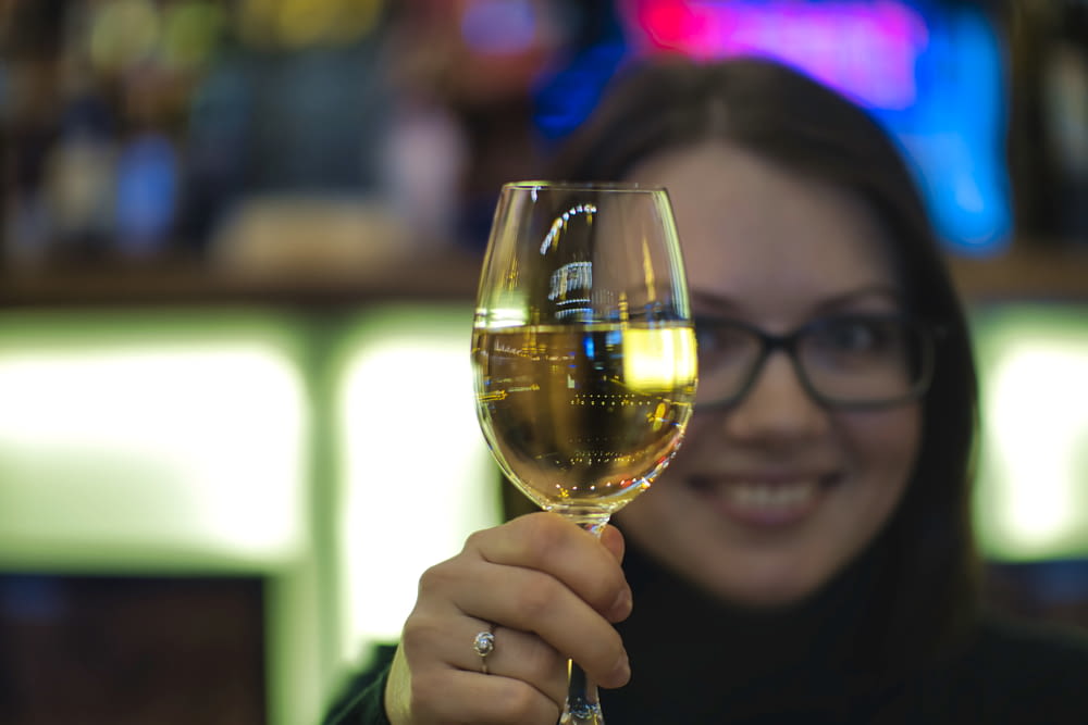 woman in black framed eyeglasses holding clear wine glass