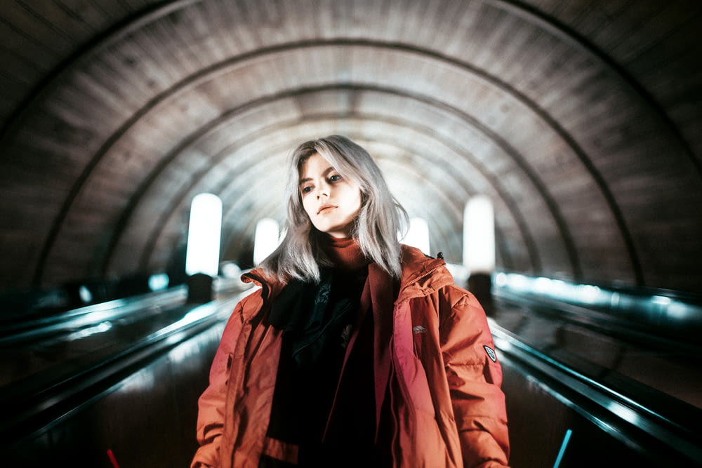 woman in red coat standing on tunnel