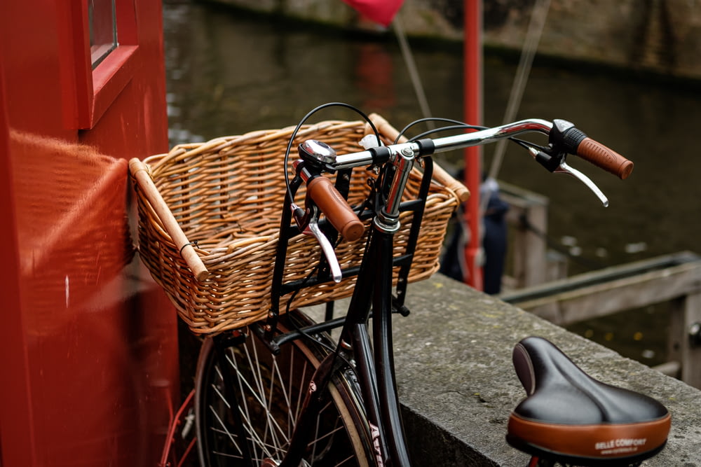 black city bike with brown woven basket on bicycle rack