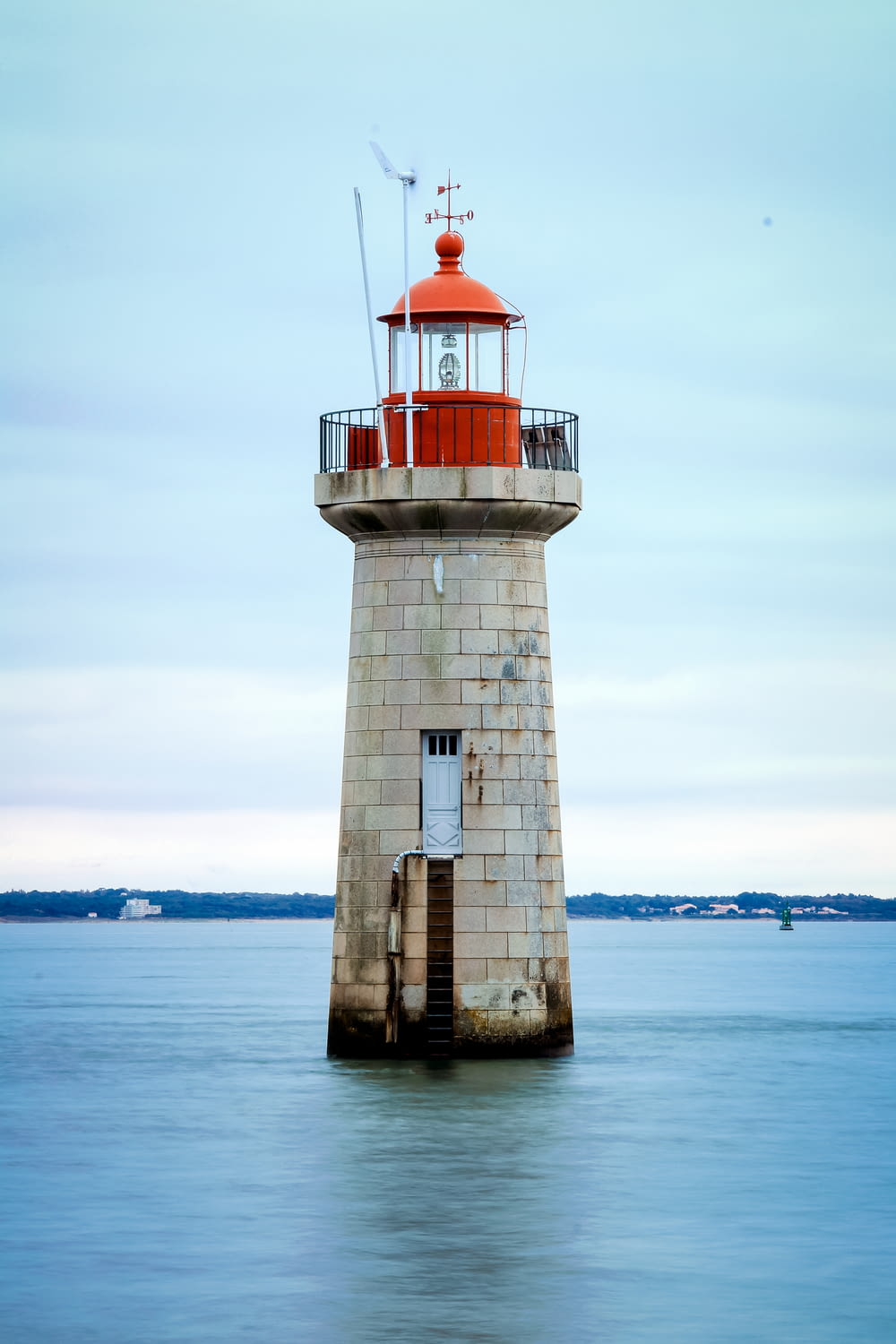white and red lighthouse on body of water during daytime