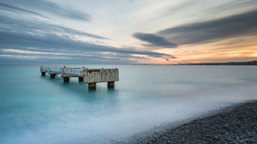brown wooden dock on sea under cloudy sky during daytime