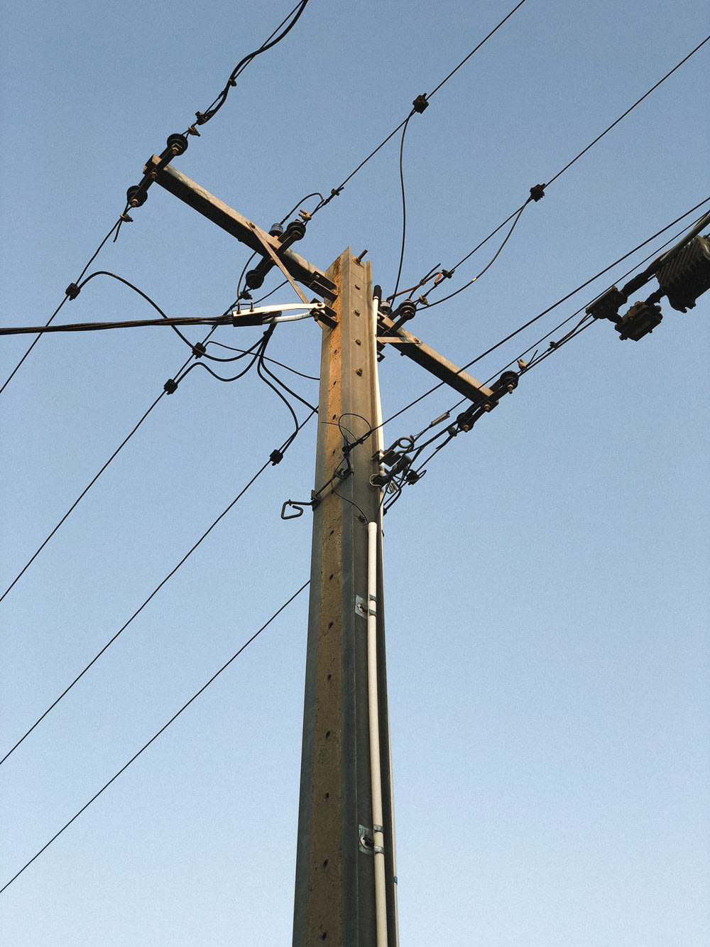 Poste eléctrico marrón bajo el cielo azul durante el día