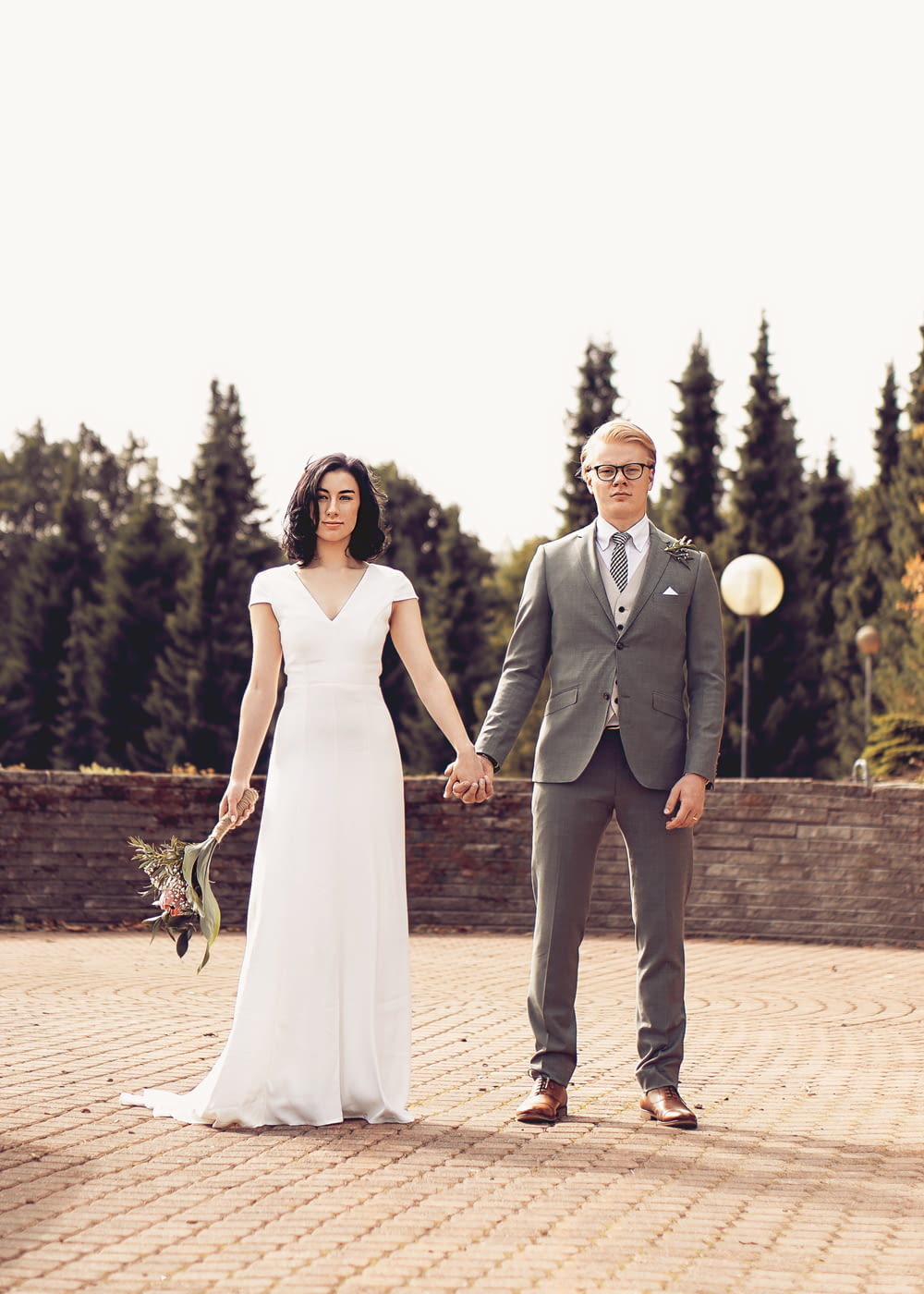 man in black suit and woman in white wedding dress standing on brown brick floor during