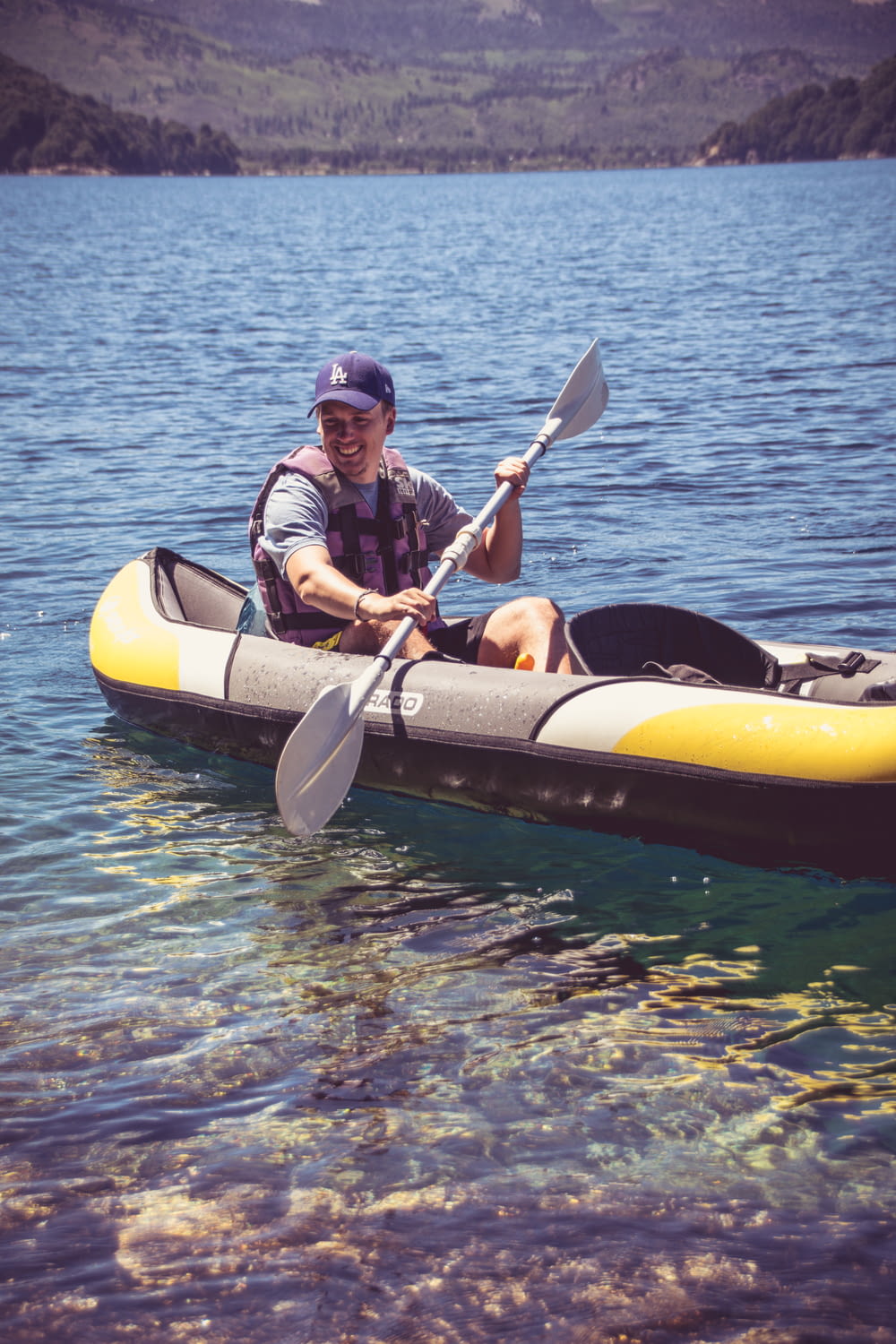 man in black and red jacket riding yellow kayak on blue body of water during daytime