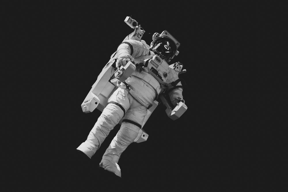 회색 음영 사진의 흰색 정장을 입은 우주 비행사