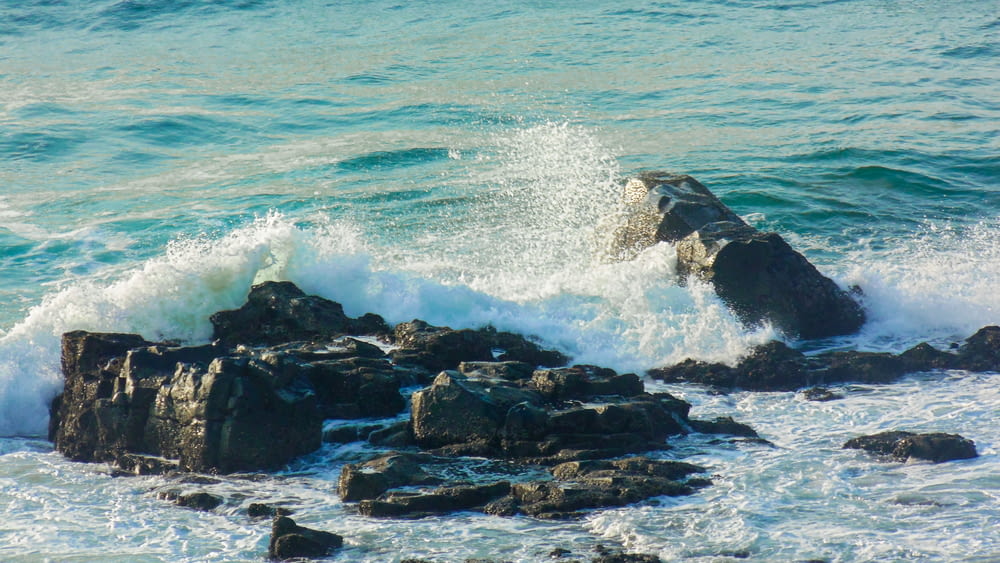 black rock formation beside sea during daytime