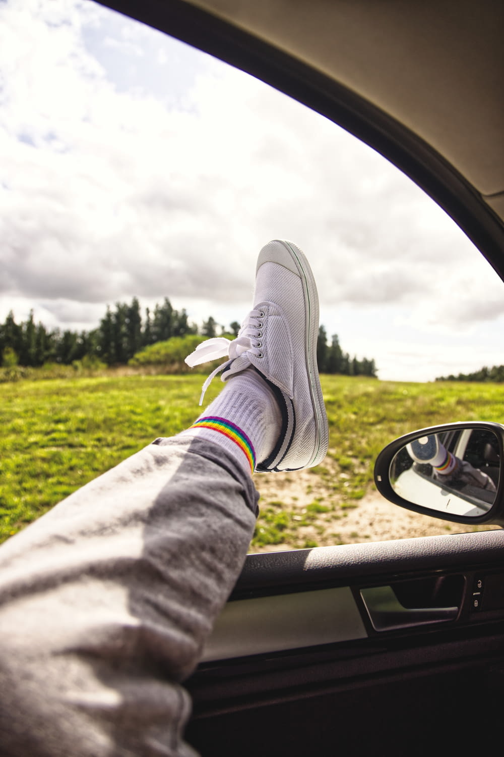 Persona con pantalones grises y zapatillas grises sentada dentro del automóvil durante el día