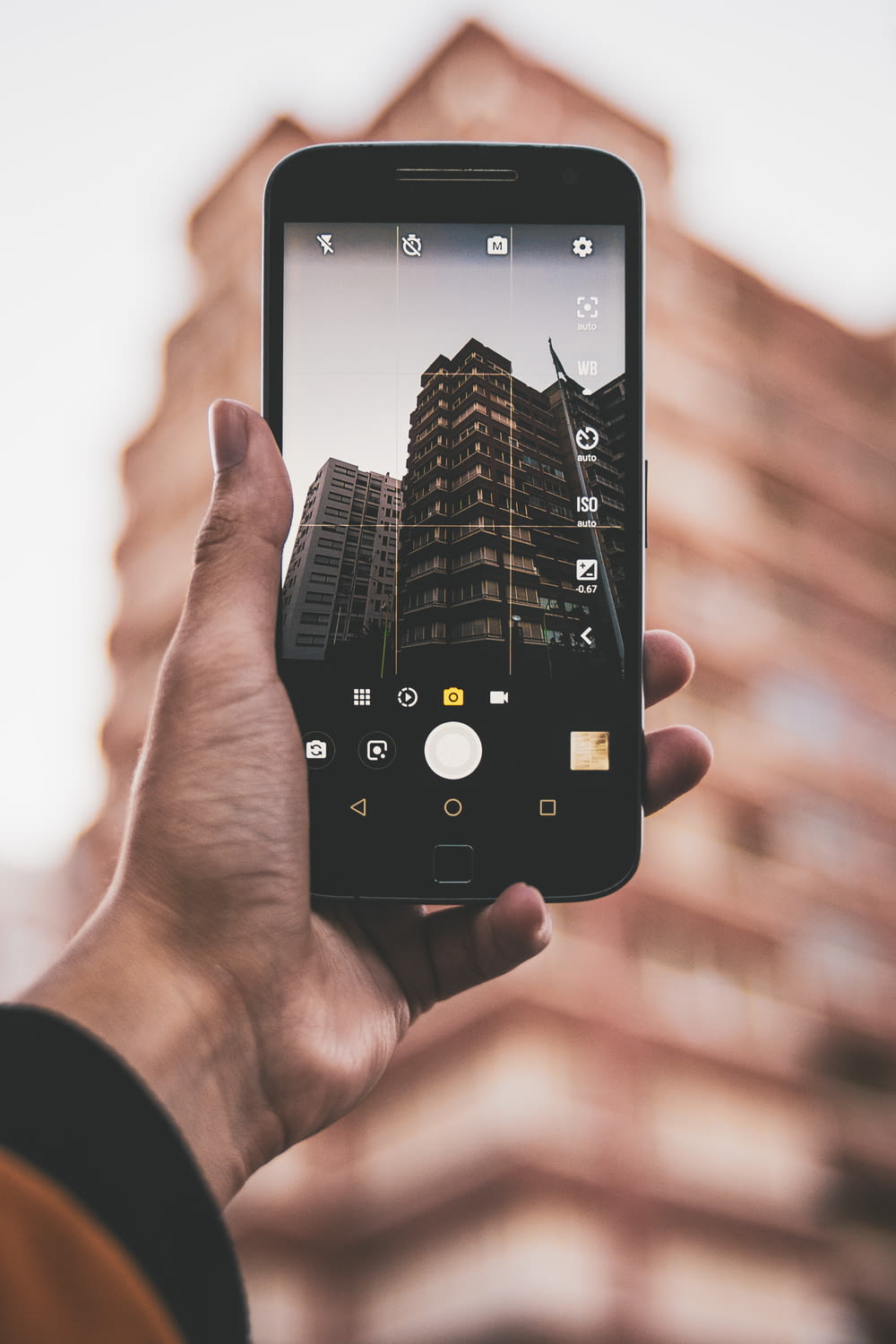 person holding black smartphone taking photo of high rise building