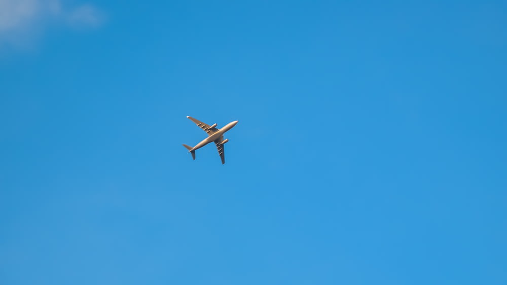 낮 동안 푸른 하늘 아래 공중에 떠 있는 하얀 비행기
