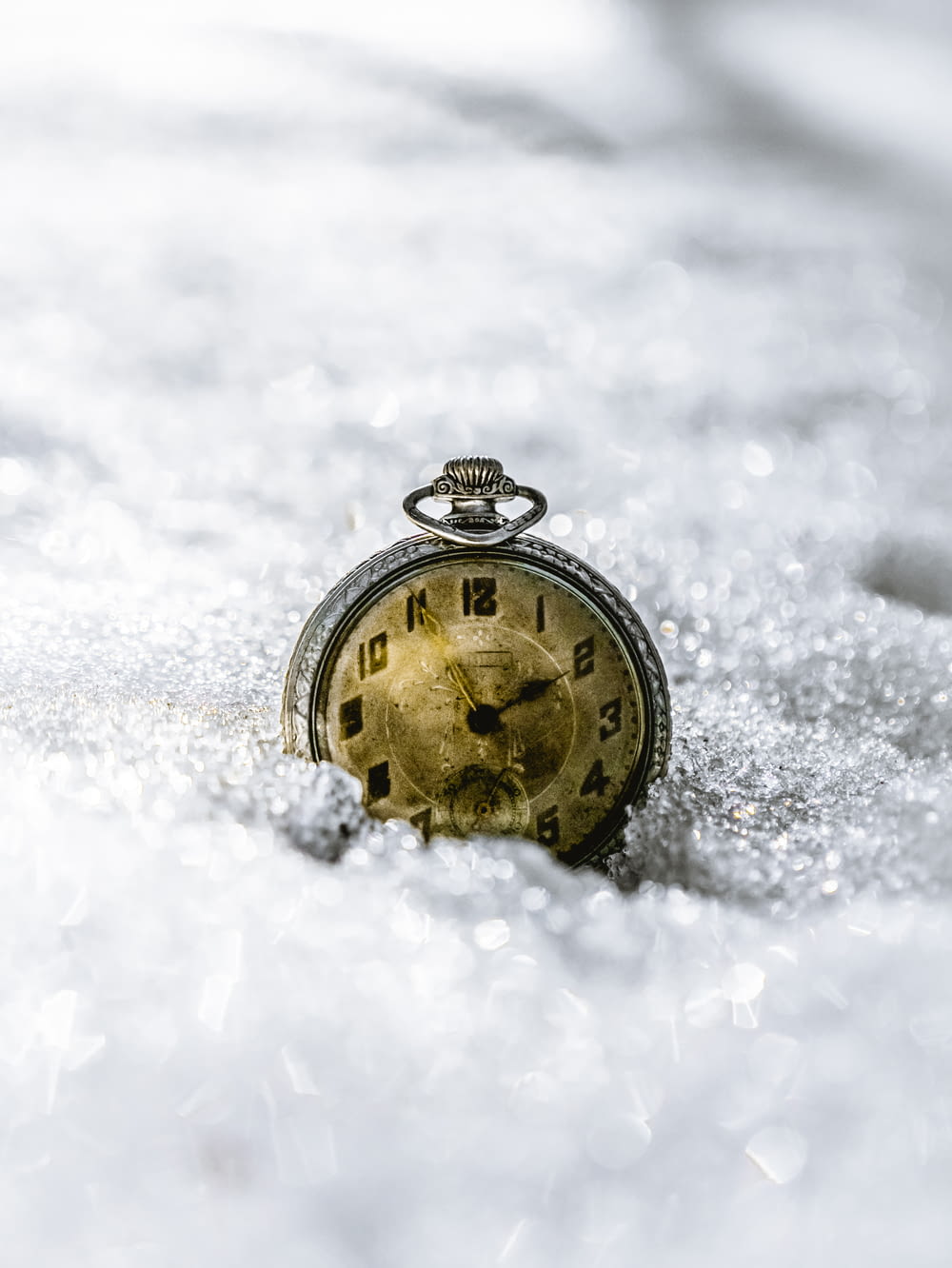 gold and black round pocket watch on snow