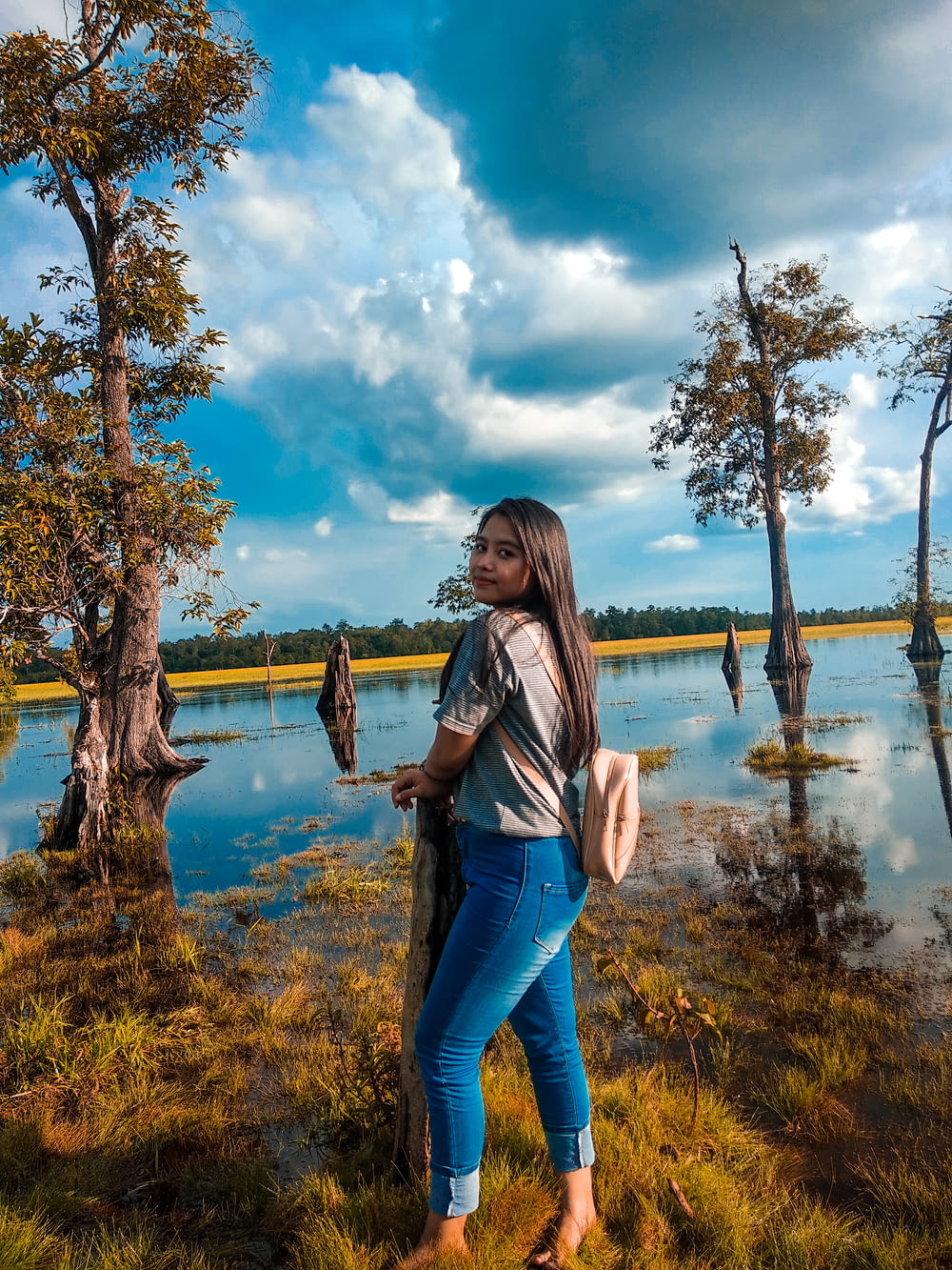 woman in blue denim jeans standing near body of water during daytime