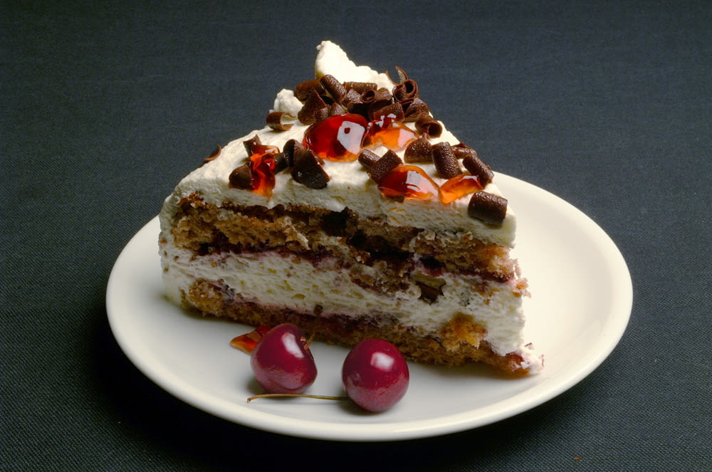 sliced cake with cherry on white ceramic plate