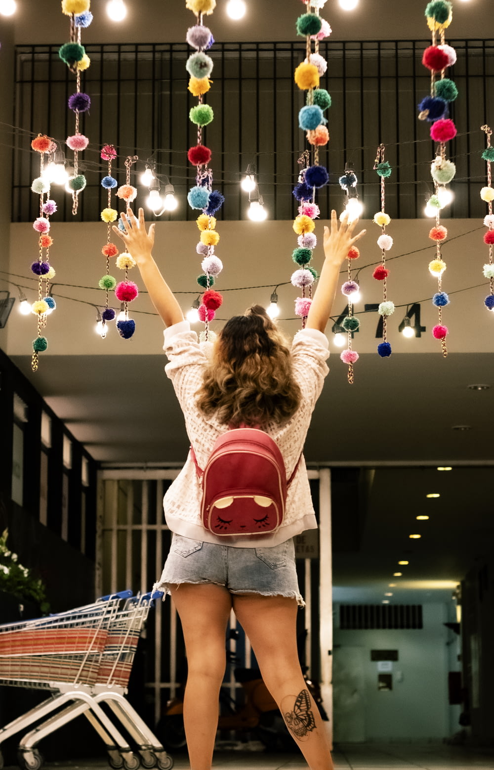 woman in red crop top and blue denim shorts standing near balloons