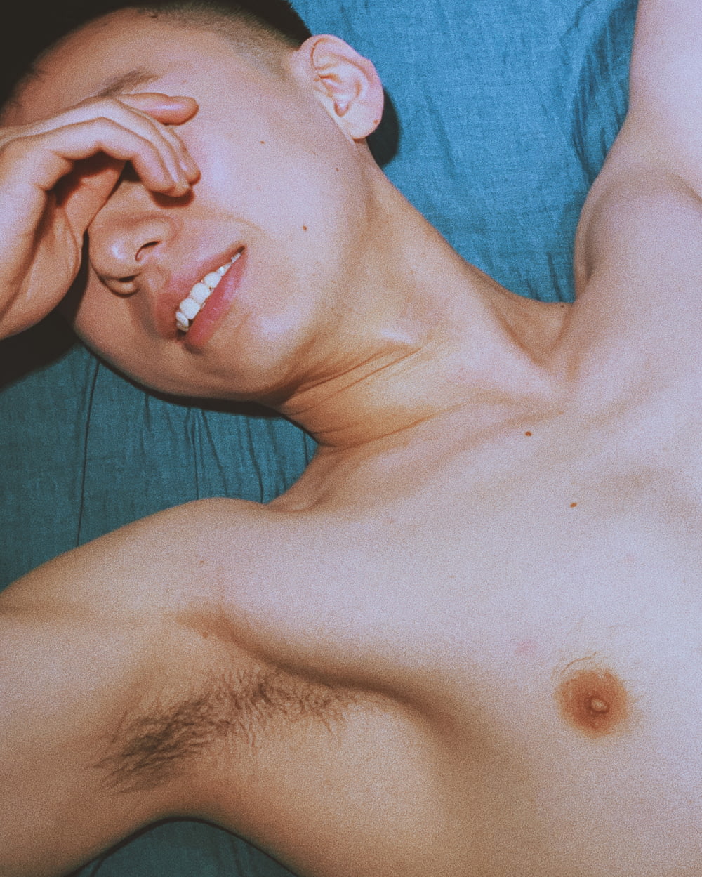 topless man lying on blue textile