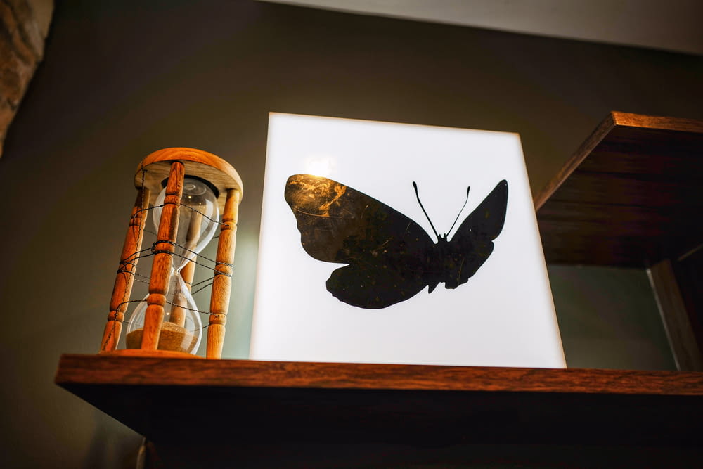 brown and black butterfly on brown wooden framed glass candle holder