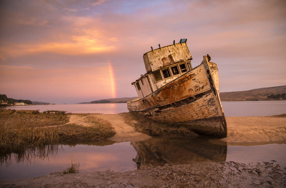 brown ship on sea shore during sunset