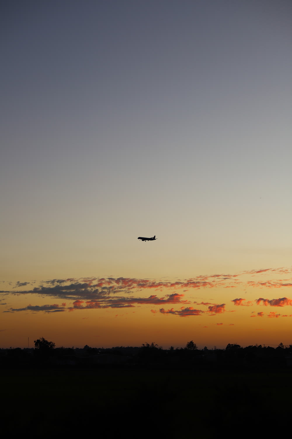 silhouette of airplane flying over the clouds during sunset