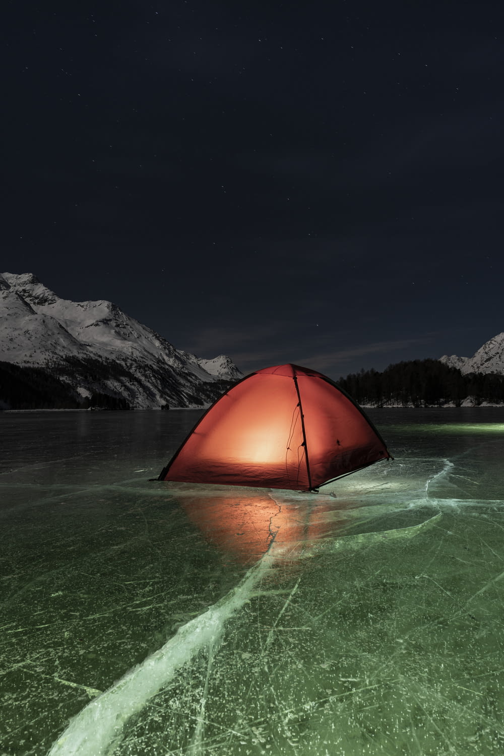 orange dome tent on green water near mountain during night time