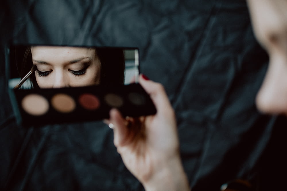 mujer sosteniendo paleta de maquillaje negra y plateada