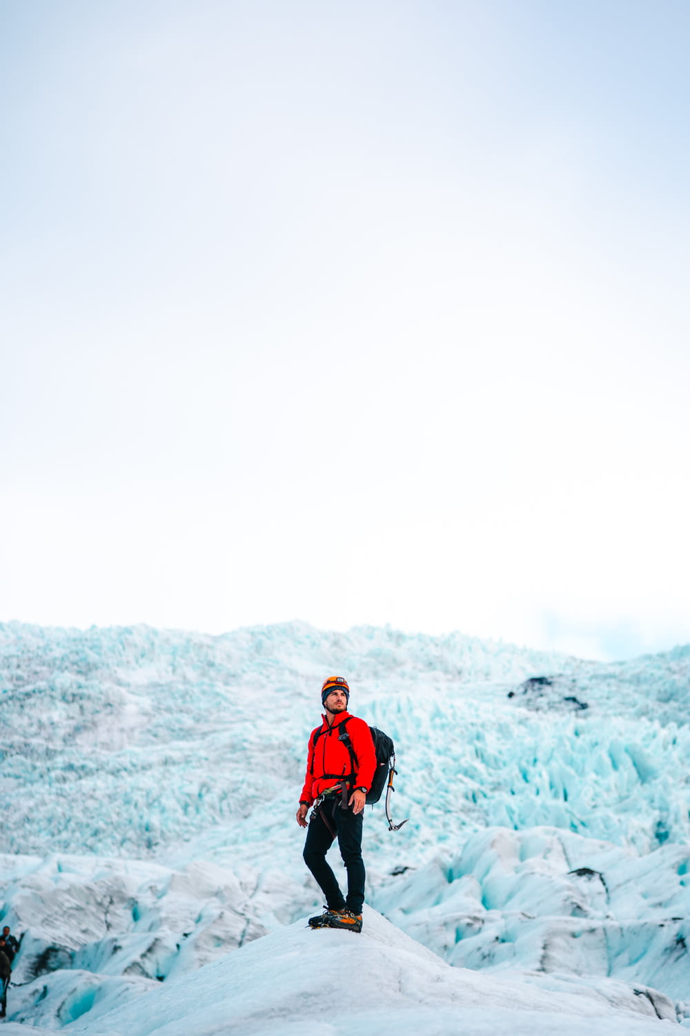 man in red jacket and black pants standing on snow covered ground