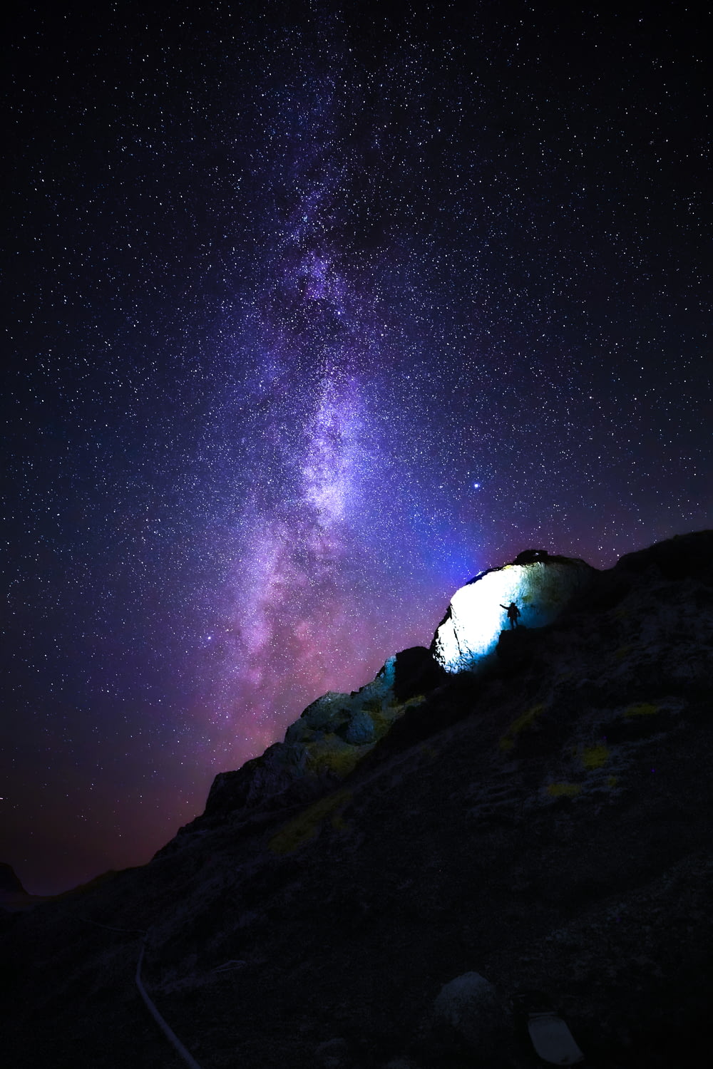 person standing on rock mountain under starry night