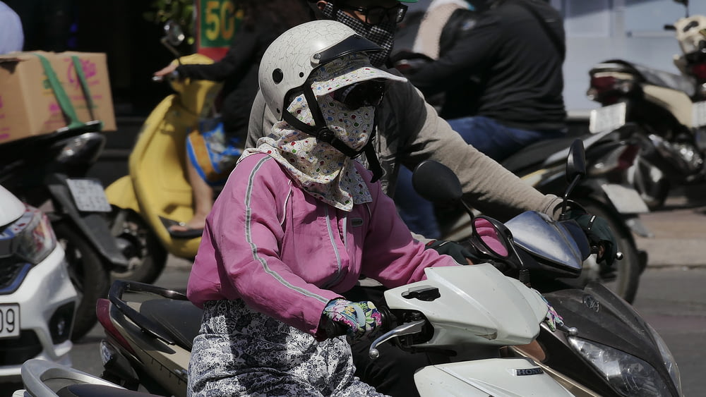 person in pink jacket wearing white helmet riding white and black motorcycle during daytime
