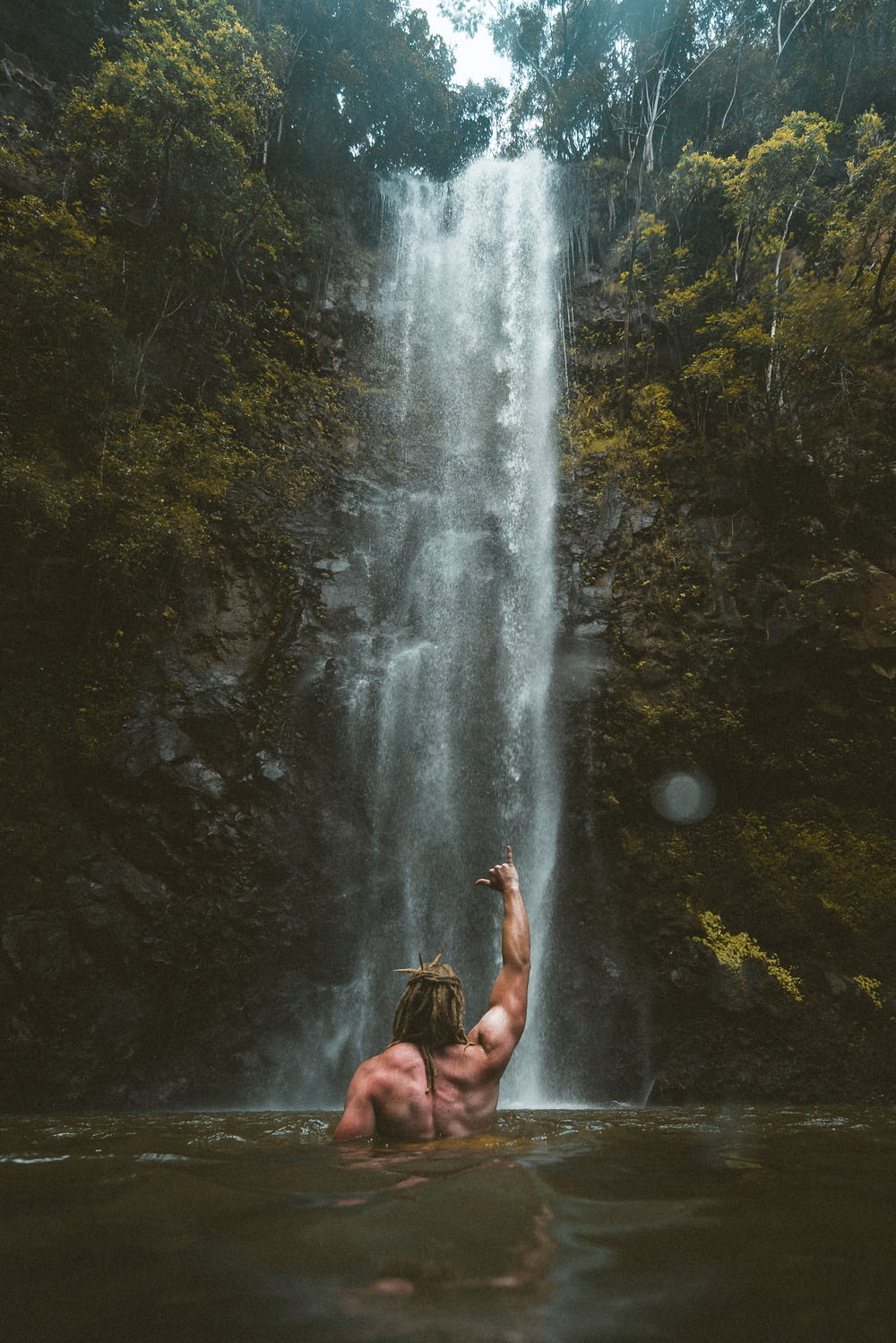 person sitting on rock near waterfalls during daytime