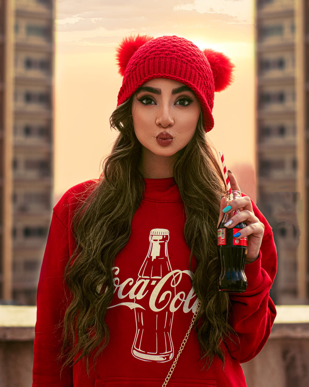 Mujer con sudadera con capucha roja sosteniendo una botella de Coca Cola