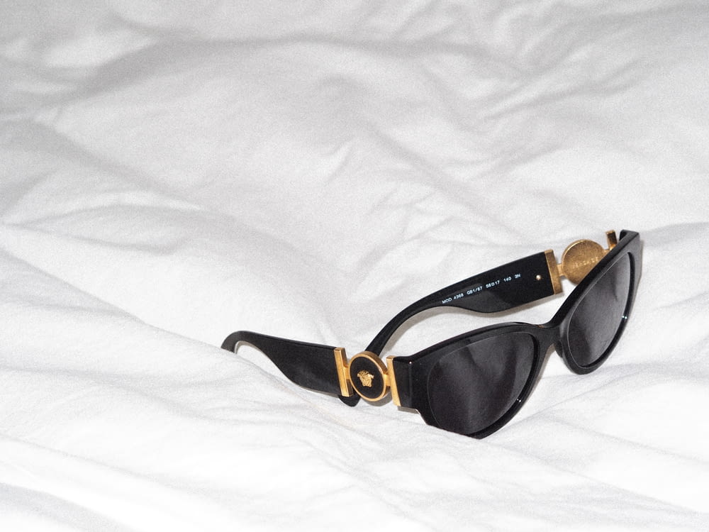 a pair of sunglasses laying on top of a bed
