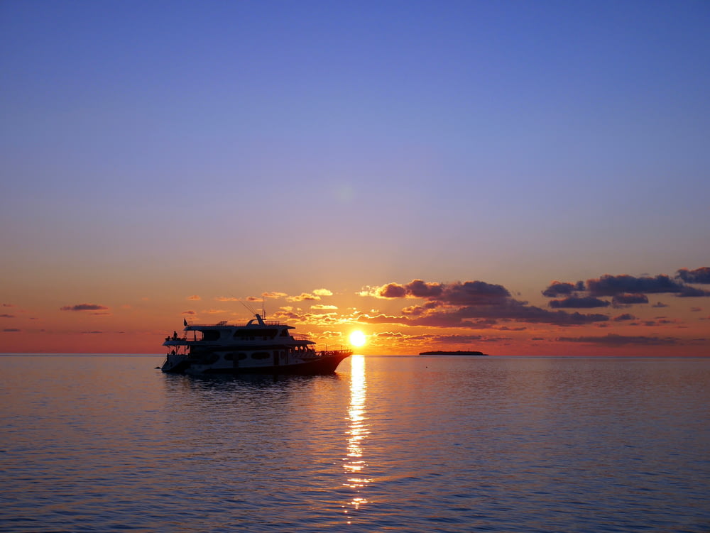 Weißes Boot auf See bei Sonnenuntergang