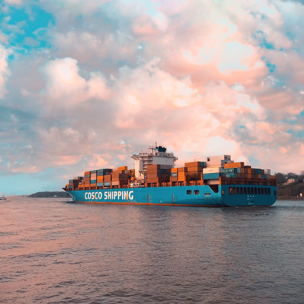 blue cargo ship on sea under cloudy sky during daytime