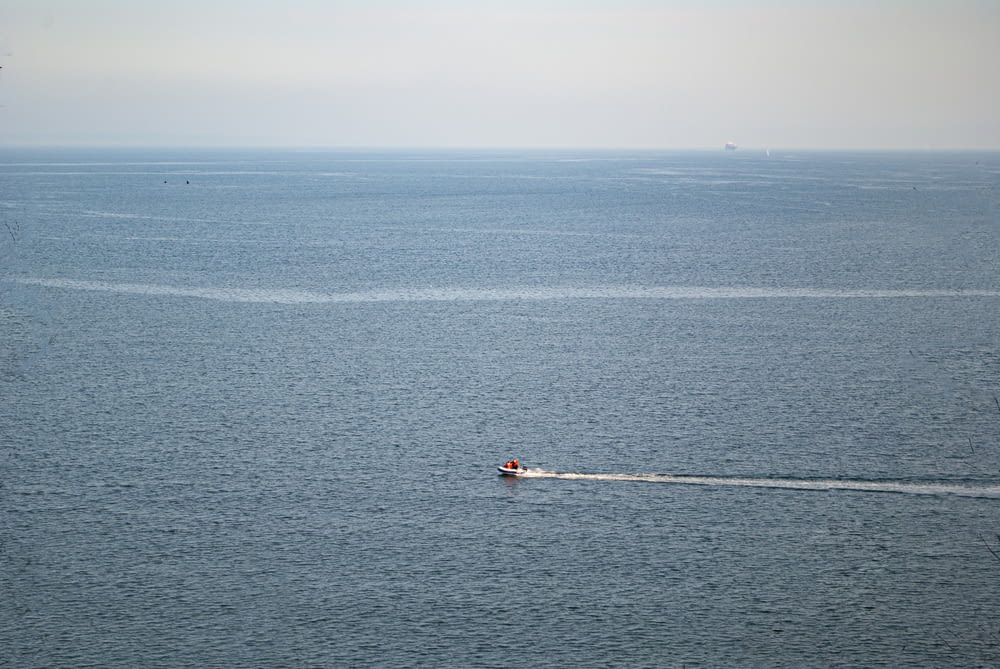 person in red shirt riding on white boat on blue sea during daytime