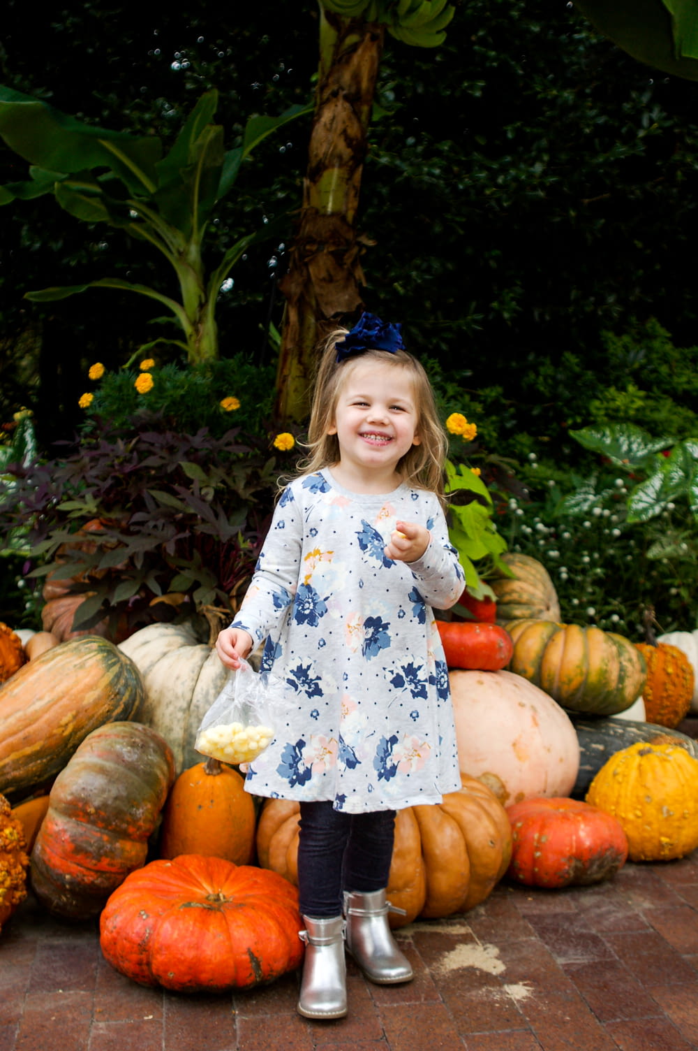 girl in white and blue floral dress standing on pumpkin field during daytime