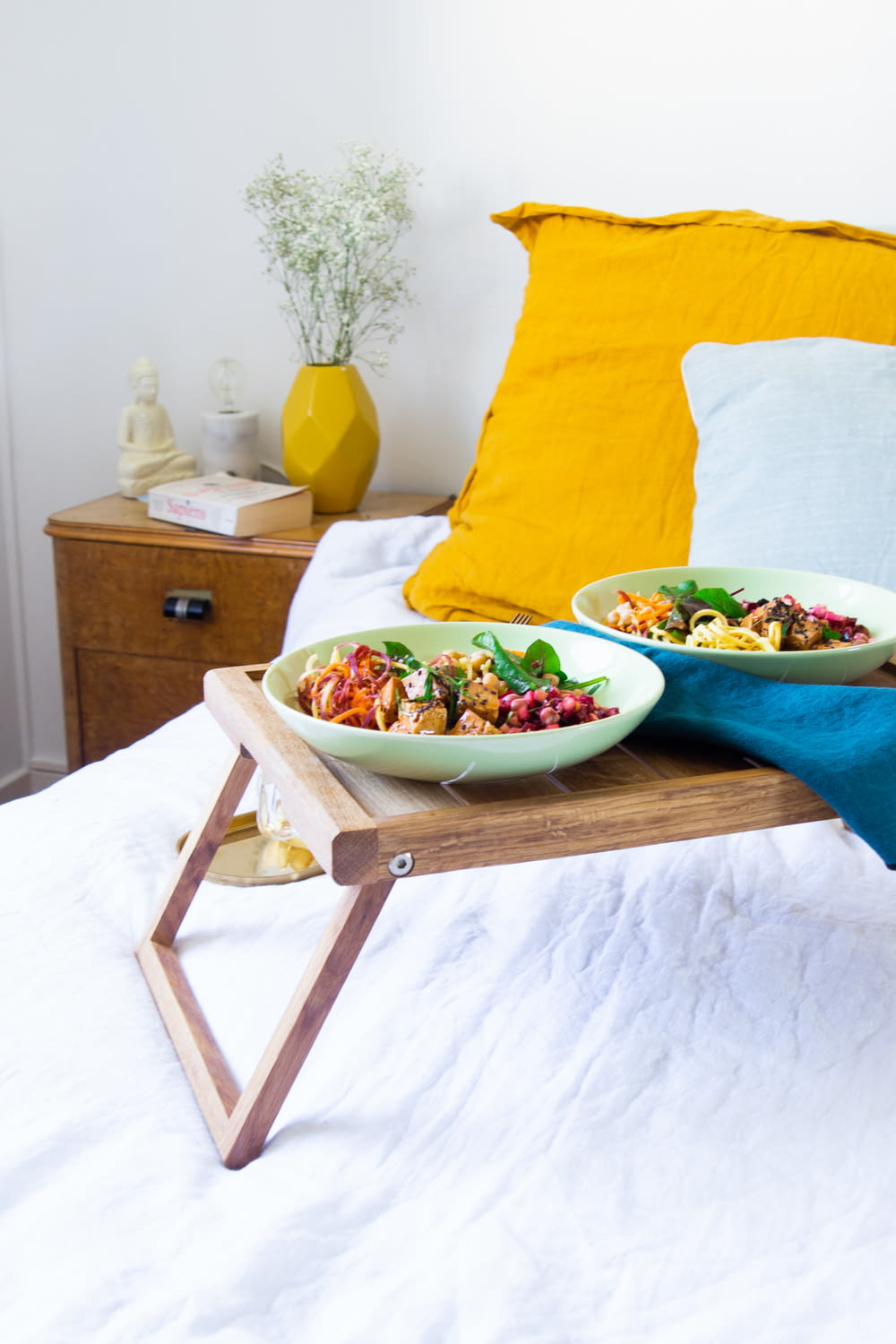 vegetable salad on white ceramic bowl beside yellow throw pillow on brown wooden table