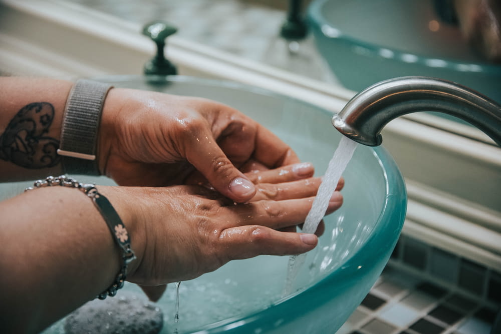 person washing hand on blue plastic basin
