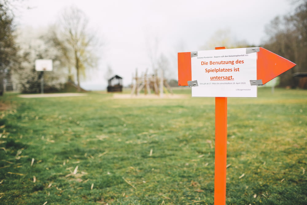 Panneau de signalisation orange et blanc sur un champ d’herbe verte pendant la journée