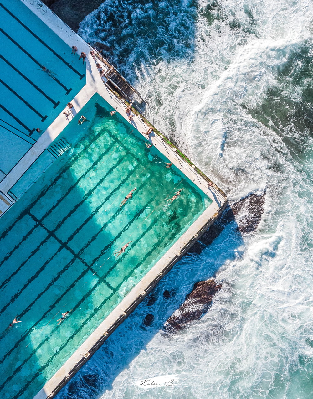 blue and brown swimming pool beside blue and white ocean water during daytime