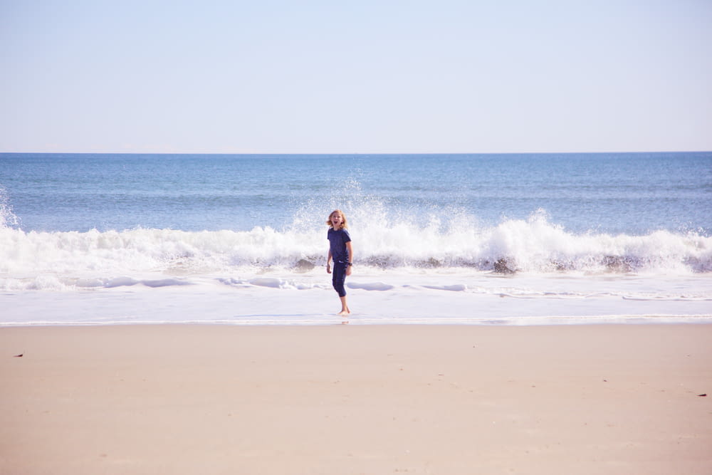昼間のビーチを歩く黒いドレスの女性