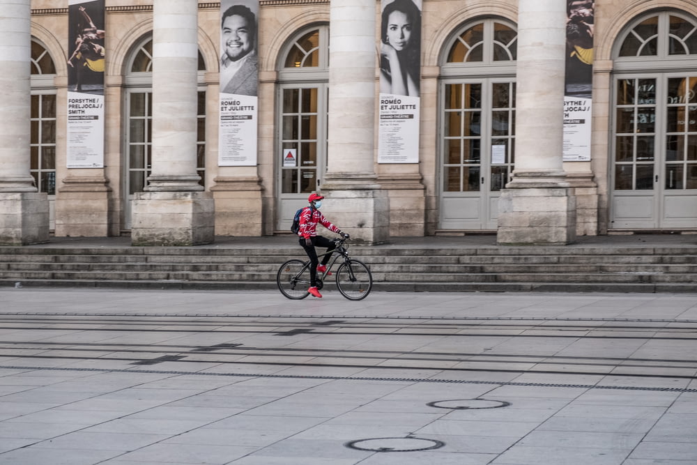 man in red jacket riding bicycle on sidewalk during daytime