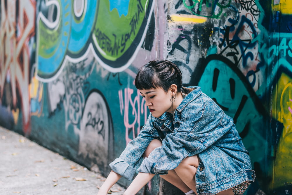 girl in blue denim jacket sitting on concrete bench