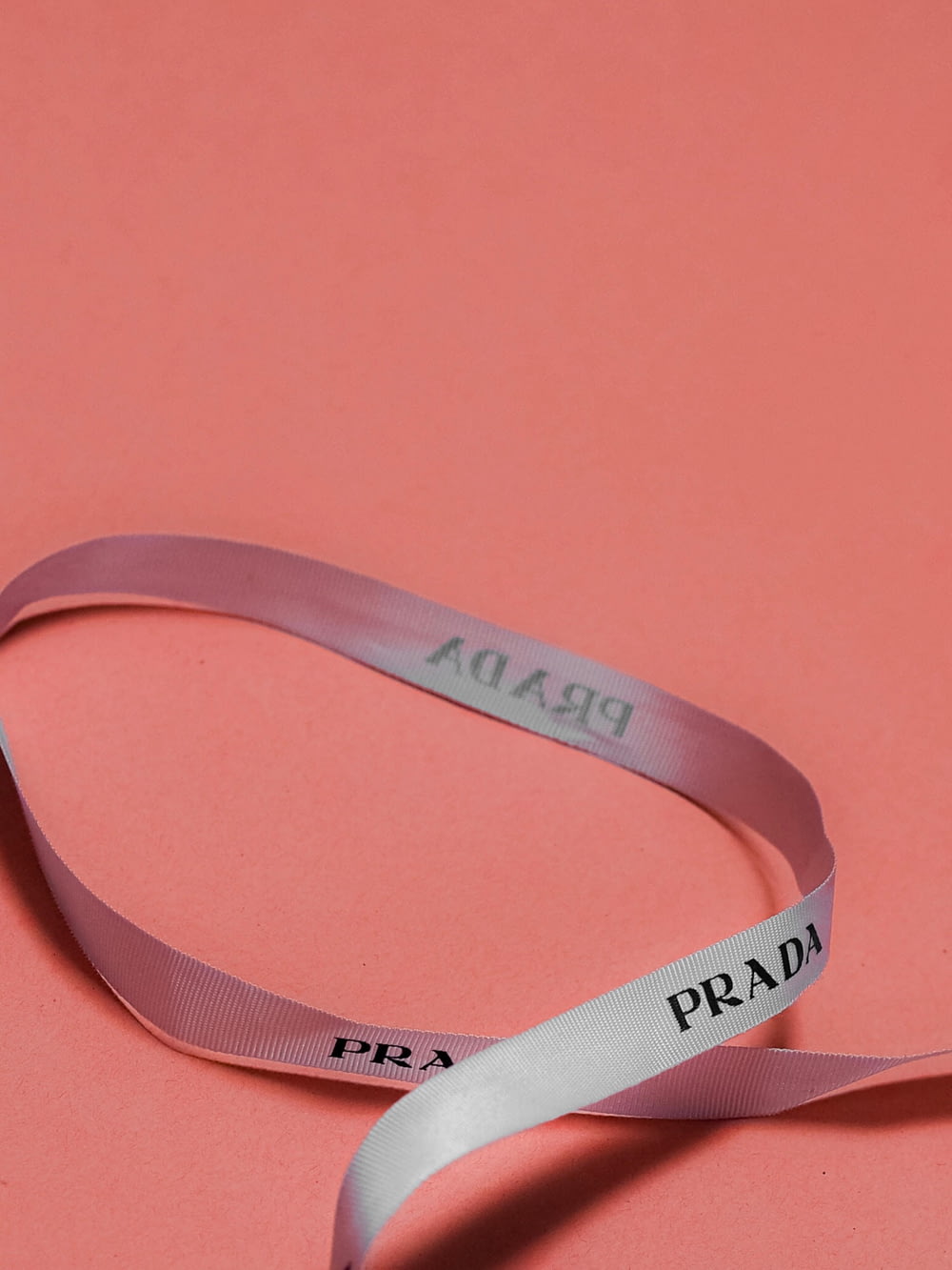 a pink ribbon with the word prada on it