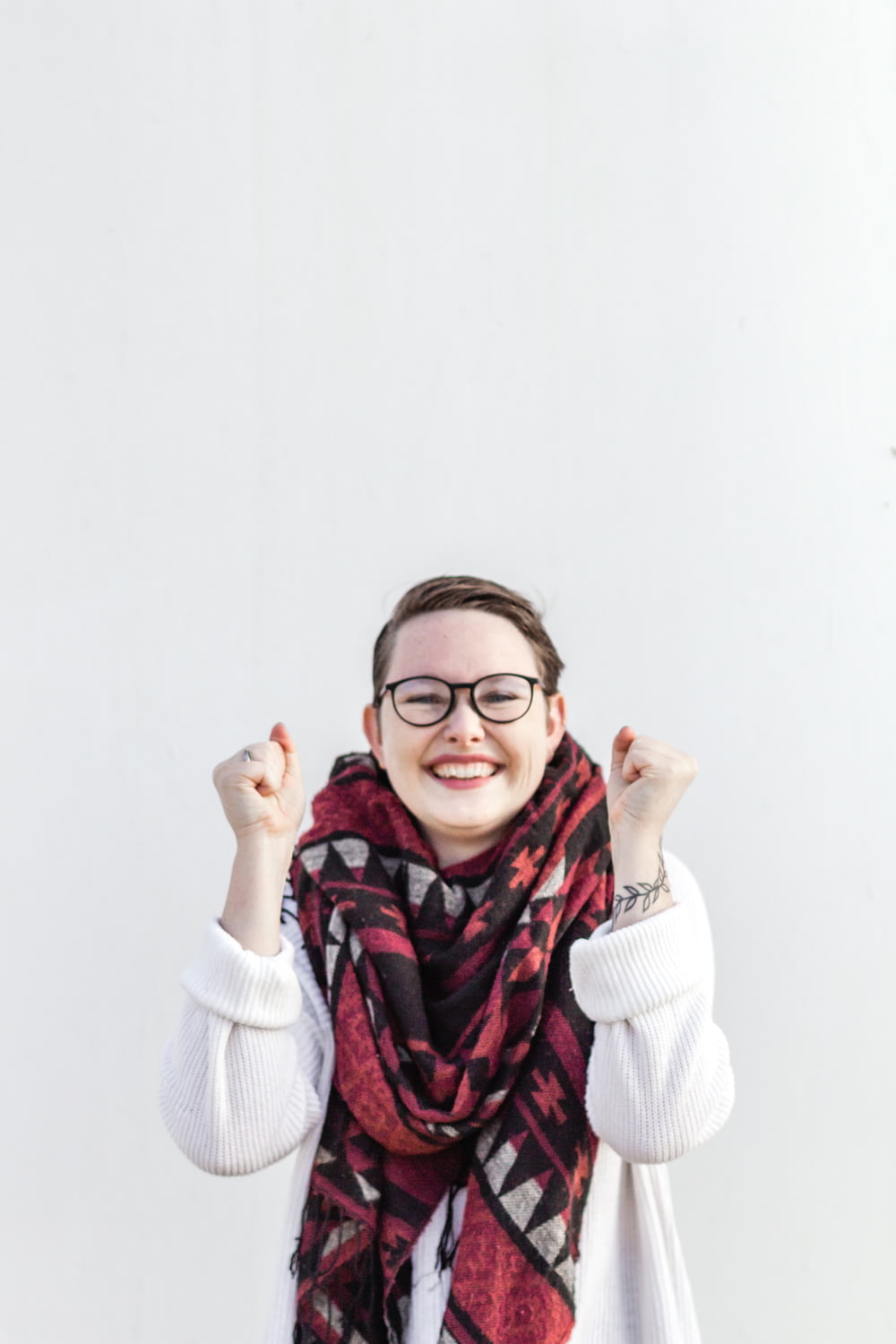 Frau im weißen Pullover mit rotem Schal und schwarz gerahmter Brille