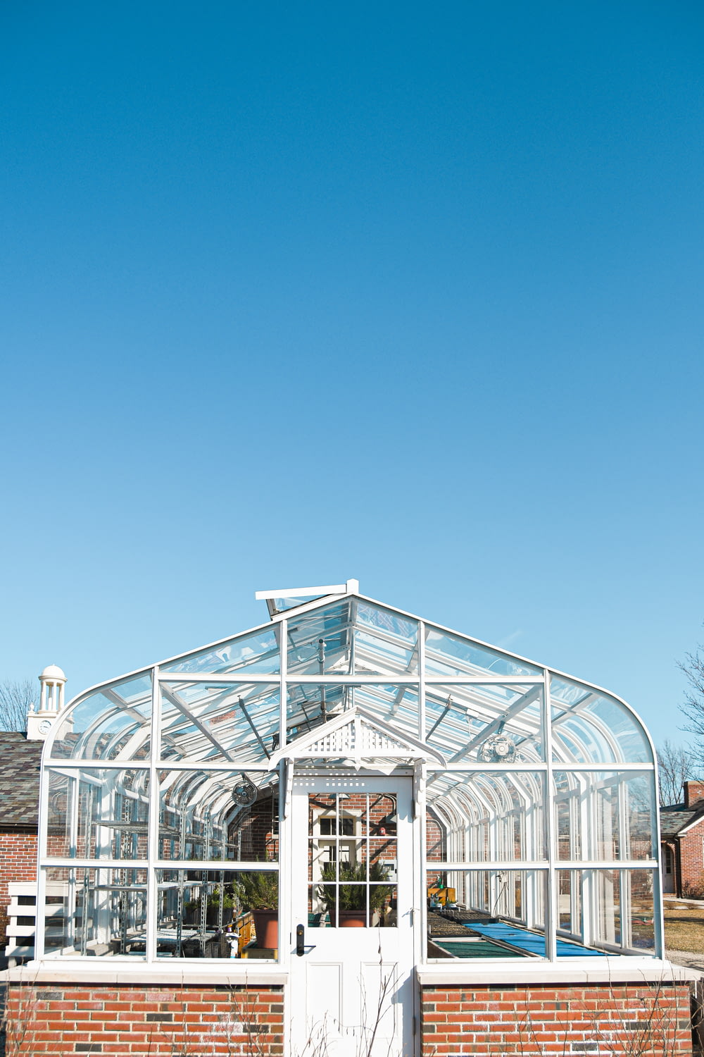 Edificio de vidrio con marco de metal blanco bajo el cielo azul durante el día