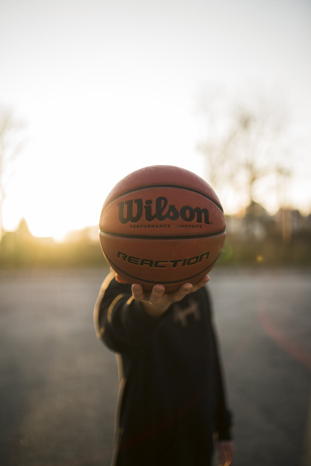 person holding brown basketball during daytime