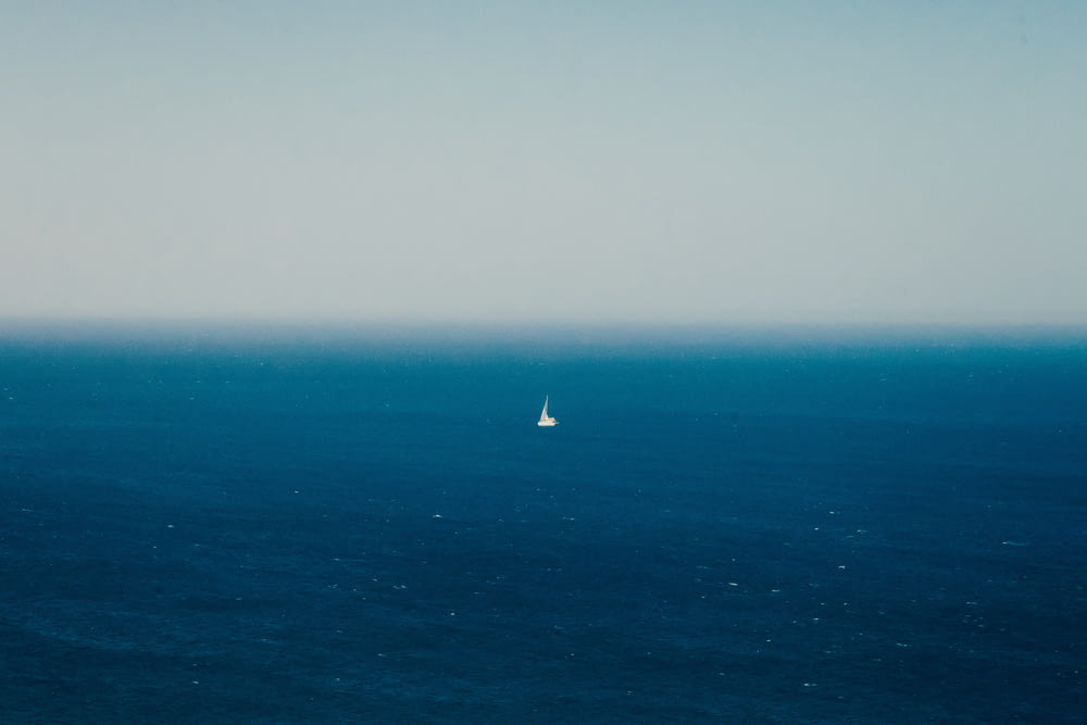 昼間の青い海に浮かぶ白い帆船